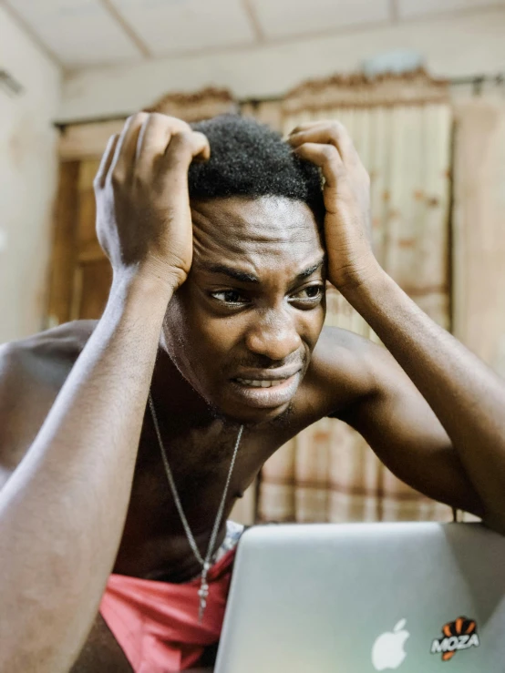 a man sitting in front of a laptop computer, by Chinwe Chukwuogo-Roy, trending on pexels, renaissance, giga chad crying, with his hands in his hair, lgbtq, thin scar on his forehead