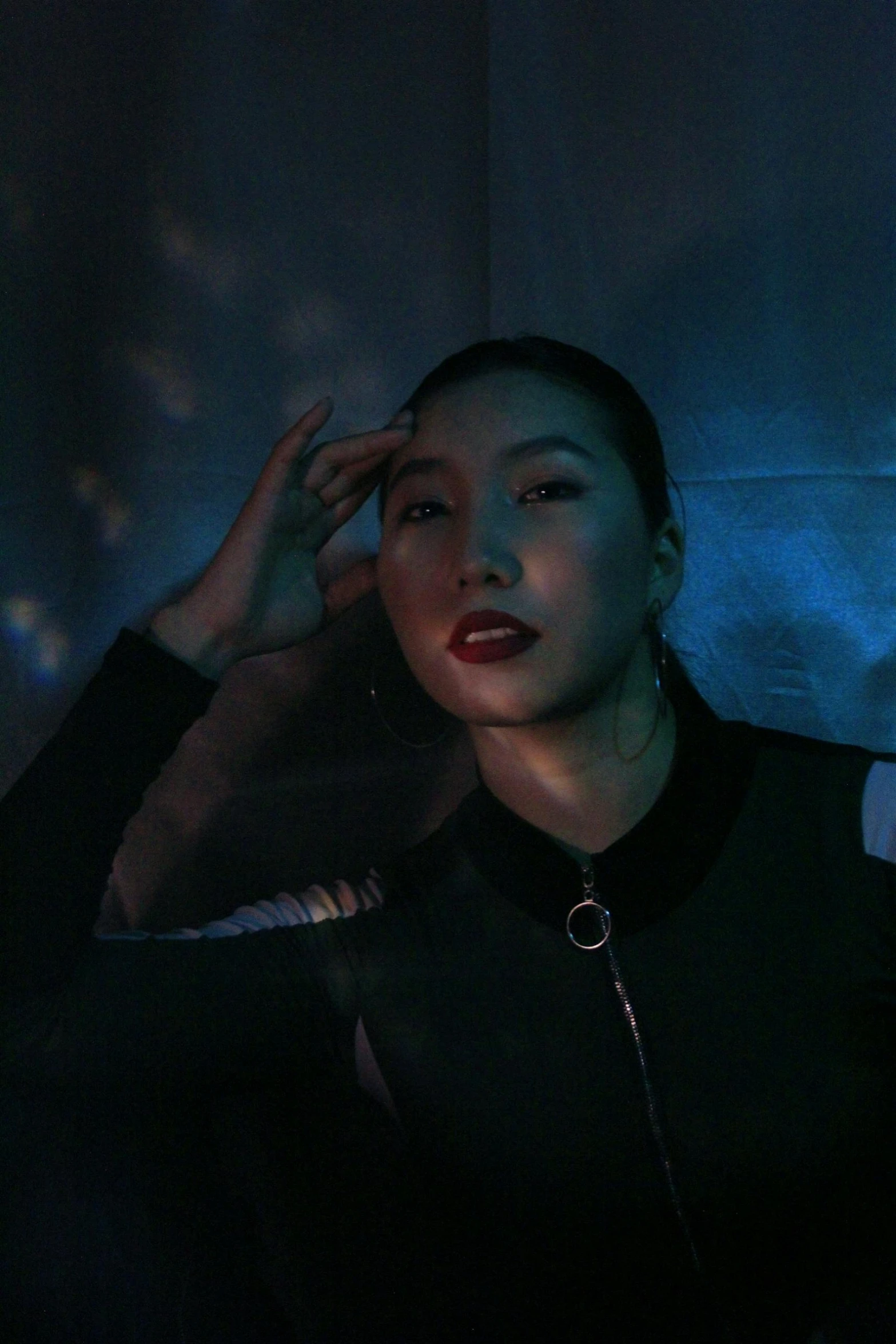 a woman in a black jacket posing for a picture, an album cover, inspired by Gao Cen, unsplash, star trek asian woman, blue light, steven klein, grainy footage