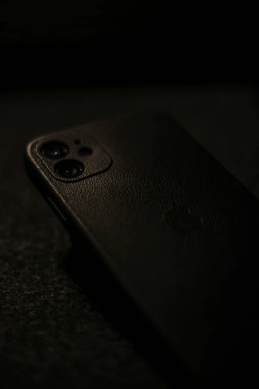 a close up of a cell phone on a table, an album cover, trending on pexels, realism, black leather, dark ominous stealth, iphone 12, 2 5 6 x 2 5 6