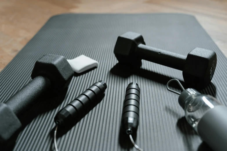 a pair of dumbbells sitting on top of a yoga mat, a still life, by Carey Morris, trending on pexels, hurufiyya, black wired cables, two crutches near bench, thumbnail, pins of light