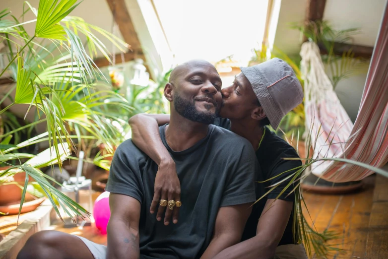 a man and a woman sitting next to each other, pexels contest winner, tropical houseplants, lesbian embrace, african aaron paul, bald on top