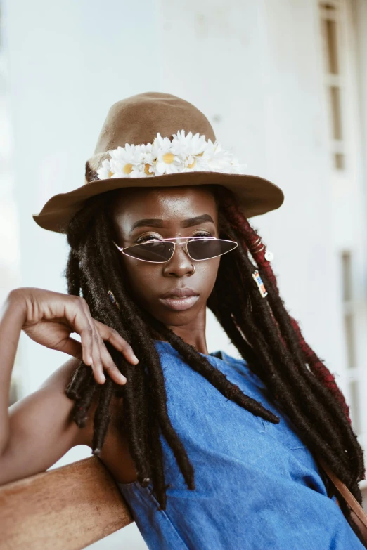 a woman sitting on a bench wearing a hat and glasses, inspired by Ras Akyem, trending on pexels, afrofuturism, dreadlock breed hair, flowers, waist high, portrait of tall