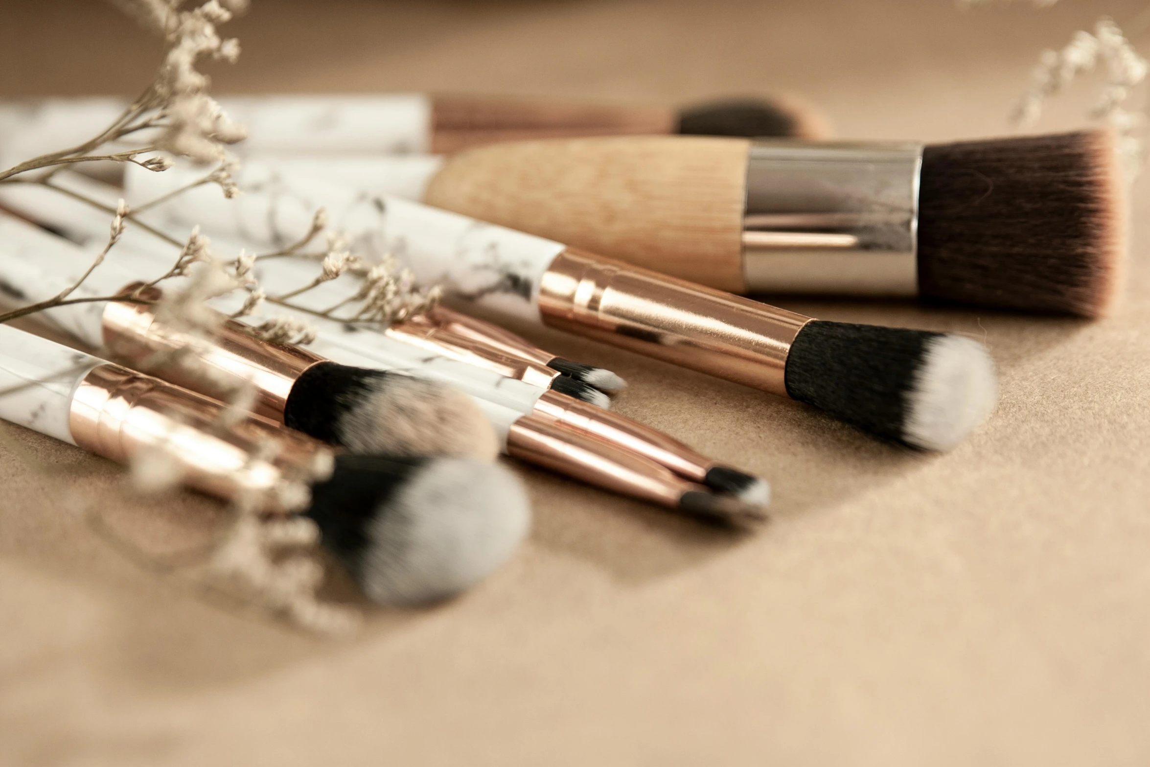 a bunch of makeup brushes sitting on top of a table, photorealism, exquisite marble details, ivory and copper, stylised, rustic