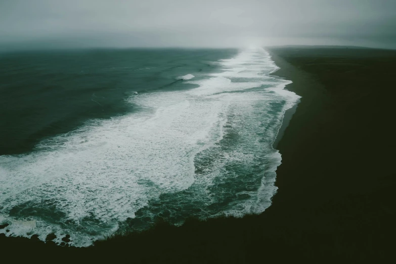 a large body of water next to a beach, an album cover, unsplash contest winner, offshore winds, dark green water, sea of milk, dark overcast weather