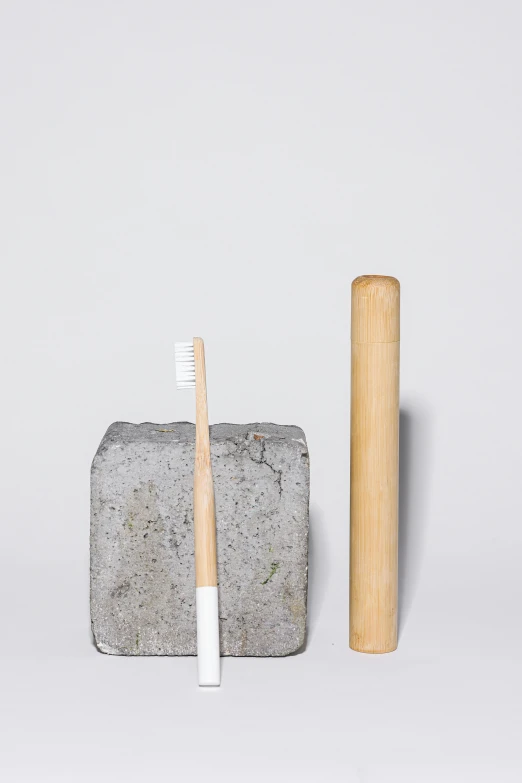 a toothbrush sitting next to a block of cement, inspired by Tooth Wu, minimalism, made of bamboo, detailed product image, disassembled, moon shine