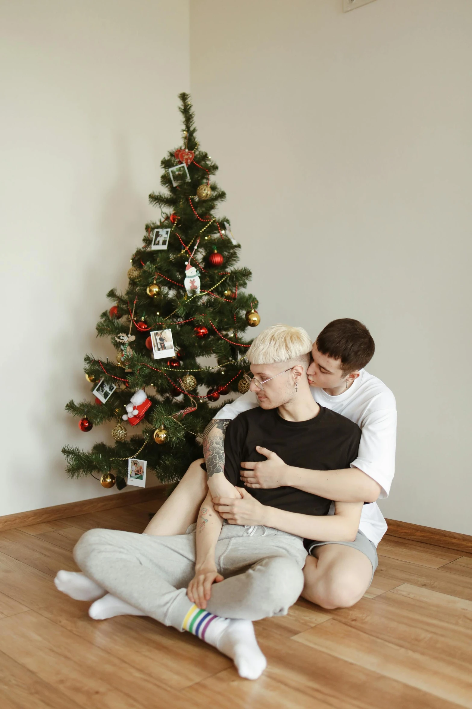 a man and a woman sitting in front of a christmas tree, by Julia Pishtar, pexels contest winner, lesbian embrace, two young men, bum, 15081959 21121991 01012000 4k