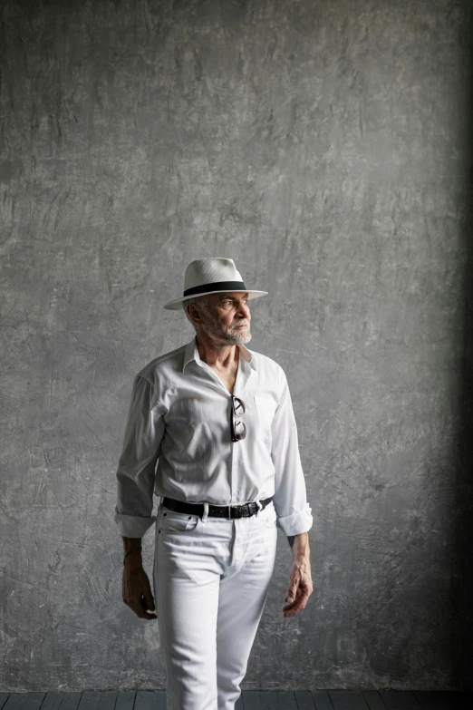 a man standing in front of a wall wearing a hat, white and silver, in style of norman foster, denys tsiperko, chalk white skin