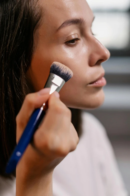 a woman brushes her face with a brush, hyperrealism, textured base ; product photos, blue, impactful, ( ultra realistic