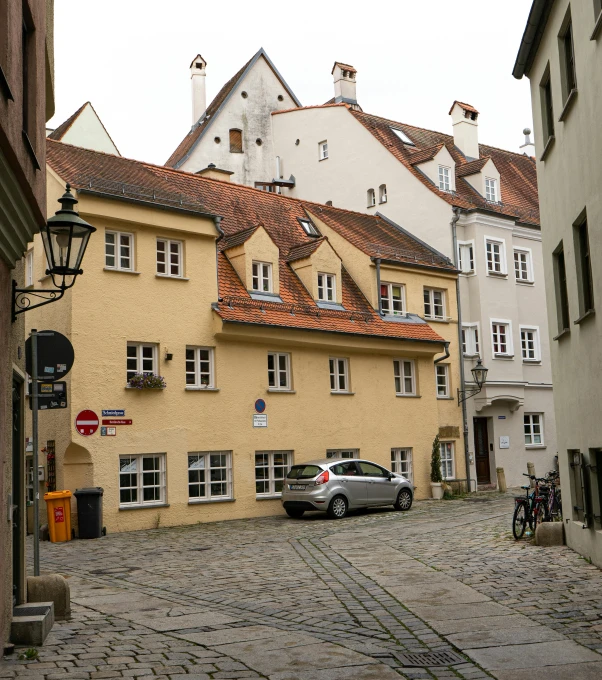 a car is parked on a cobblestone street, danube school, white buildings with red roofs, munich, an escape room in a small, no cropping