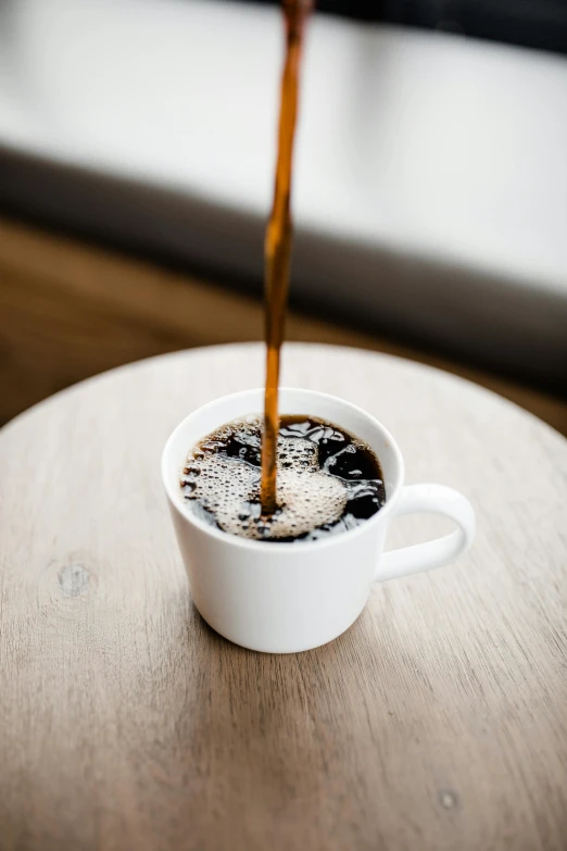 coffee being poured into a cup on a table, by Robbie Trevino, multiple stories, heavily upvoted, black, small