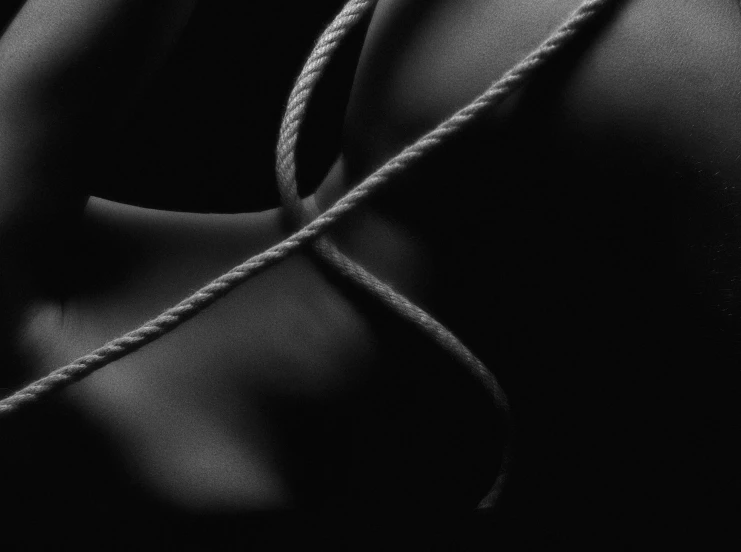 a black and white photo of a woman tied up, inspired by Robert Mapplethorpe, unsplash, lyrical abstraction, close up. macro. hyper realistic, rope, satin, black paper