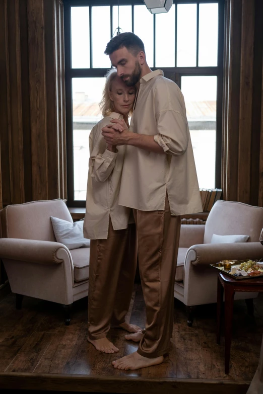 a man standing next to a woman in a living room, inspired by Albert Edelfelt, unsplash, renaissance, wearing white pajamas, intertwined full body view, ( ( theatrical ) ), cuddling