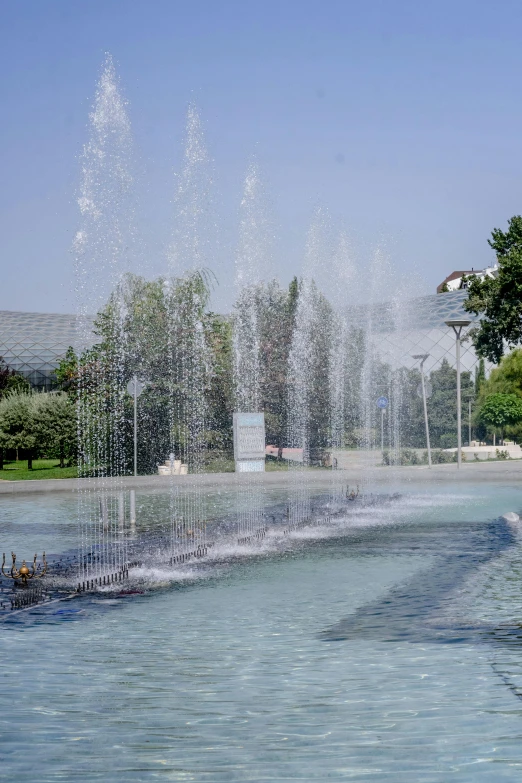 a water fountain with jets of water coming out of it, sportspalast amphitheatre, vladimir abat-cherkasov, from the distance, square