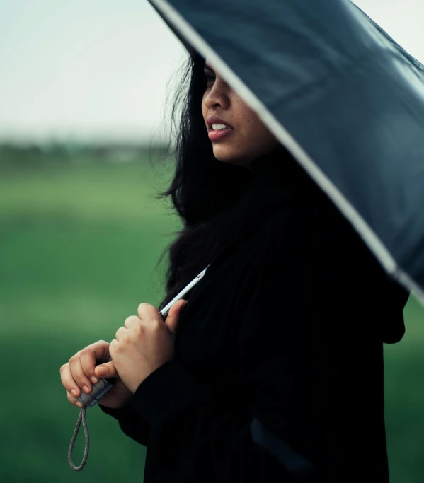 a close up of a person holding an umbrella, unsplash, black haired girl wearing hoodie, cindy avelino, profile pic, stormy