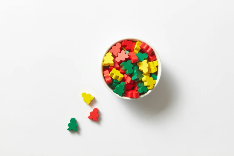 a bowl of gummy bears sitting on top of a white table, a jigsaw puzzle, inspired by Mario Bardi, isometric view, full dynamic colour, mickey mouse, product shot