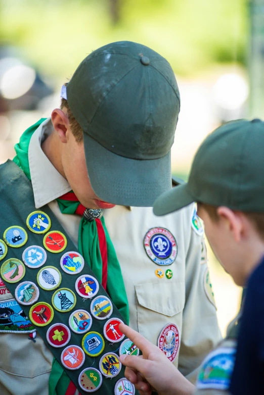 a couple of young men standing next to each other, by Terese Nielsen, trending on unsplash, boy scout troop, wearing many medallions, a green, charts