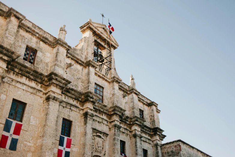 a tall building with a clock on top of it, an album cover, by Juan Giménez, pexels contest winner, quito school, francisco de zurbaran, flag, conversano, warm light