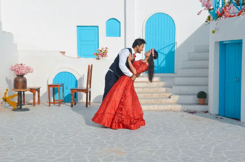 a man standing next to a woman in a red dress, pexels contest winner, arabesque, making out, blue colored traditional wear, greek setting, 15081959 21121991 01012000 4k