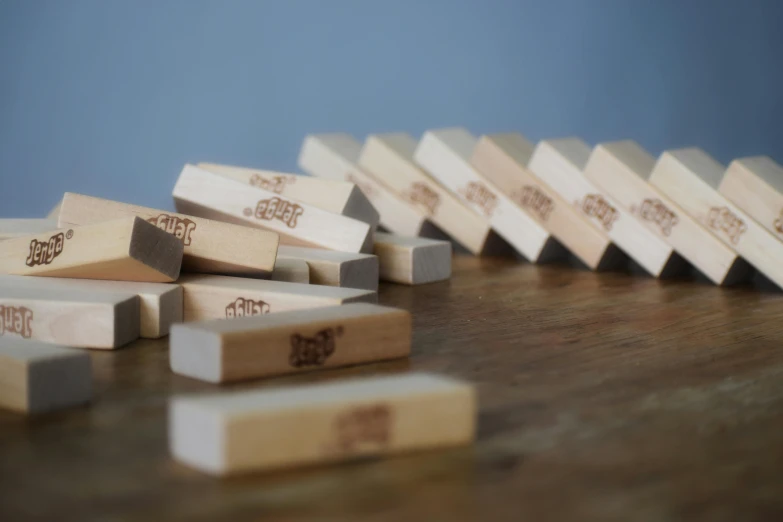 a row of dominos sitting on top of a wooden table, by Jessie Algie, falling buildings, grey, product photograph, small