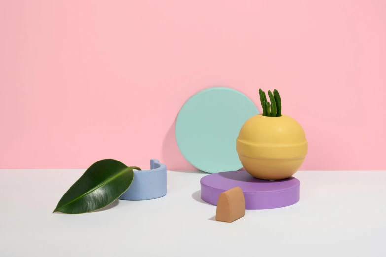 a yellow vase sitting on top of a table next to a green leaf, a still life, inspired by Jeff Koons, trending on unsplash, conceptual art, pastel pink concrete, big pods, with round cheeks, sea of parfait