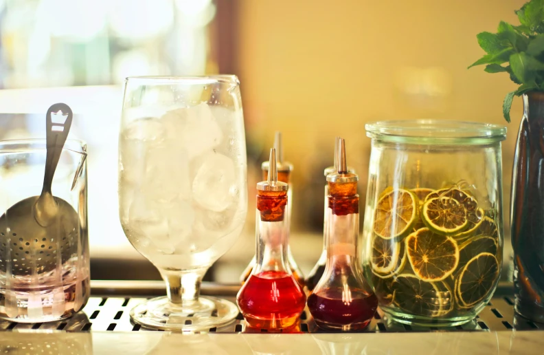 a bunch of glasses sitting on top of a counter, infused, cocktail bar, iced tea glass, vials