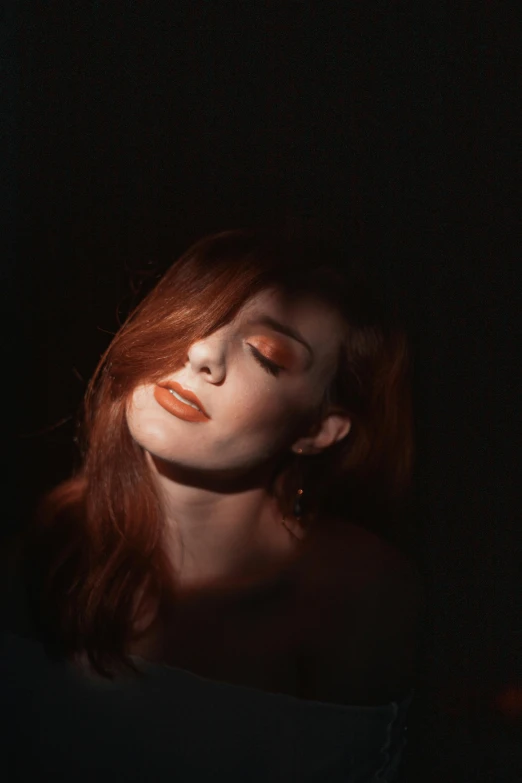 a woman sitting in the dark with her eyes closed, a portrait, inspired by Elsa Bleda, pexels contest winner, renaissance, ( redhead, light-red lips, orange hue, better known as amouranth