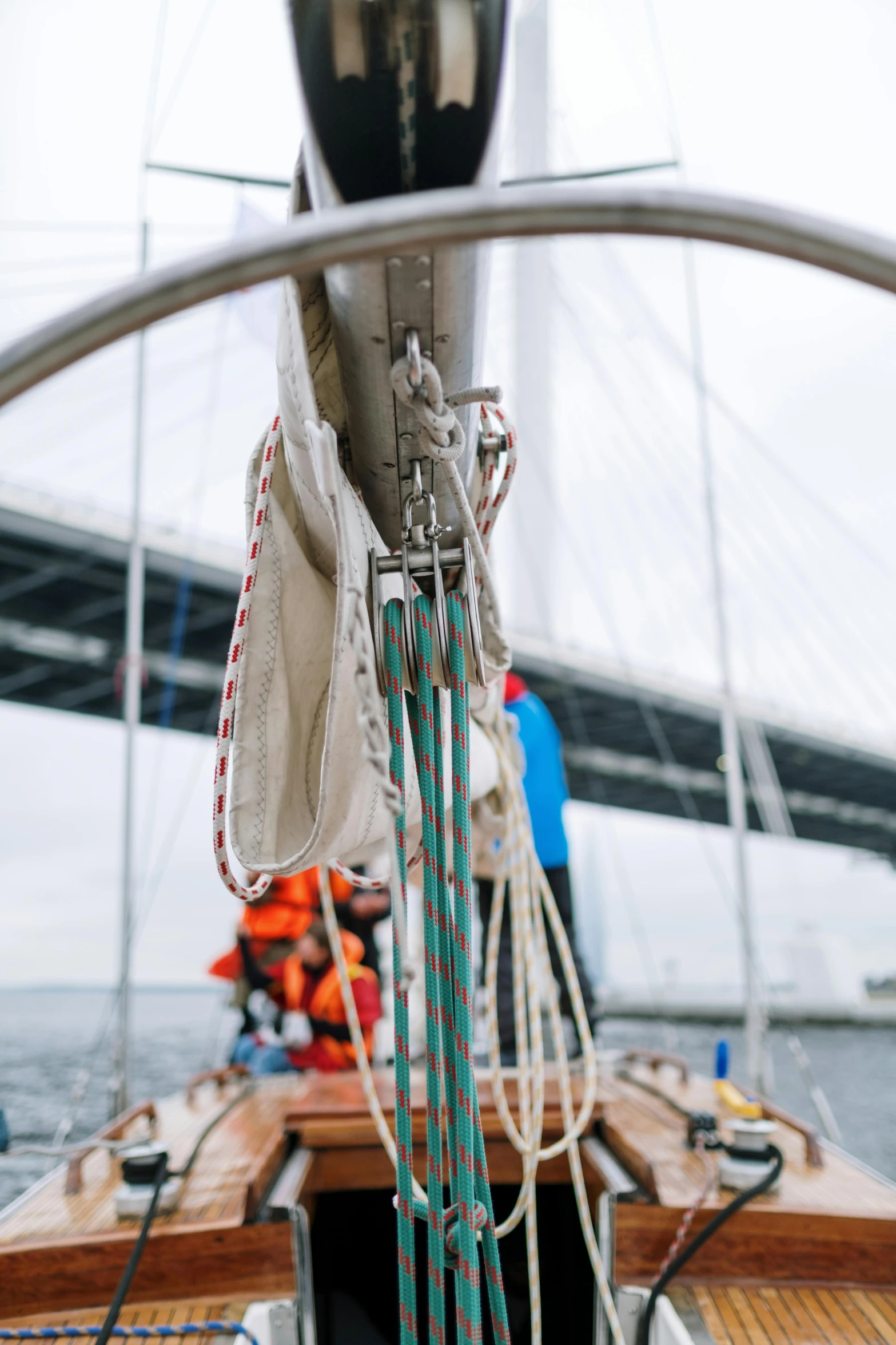 a boat on a body of water with a bridge in the background, by Ejnar Nielsen, pexels contest winner, sails and masts and rigging, helmet view, camaraderie, where a large