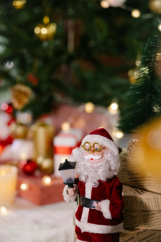 a santa claus figurine standing in front of a christmas tree, a portrait, pexels contest winner, folk art, candles in foreground, closeup of an adorable, giving gifts to people, zoomed in