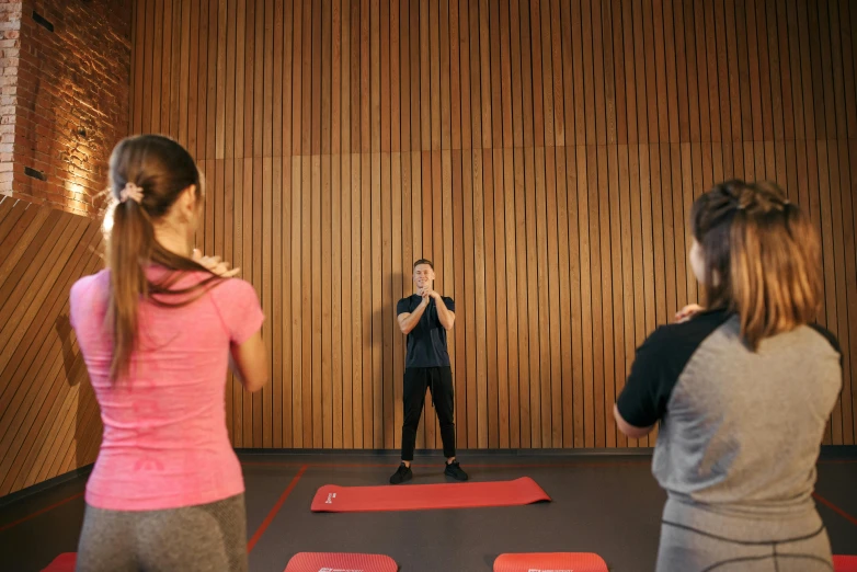 a couple of women standing on top of a red mat, unsplash, school class, man standing in defensive pose, lachlan bailey, person in foreground