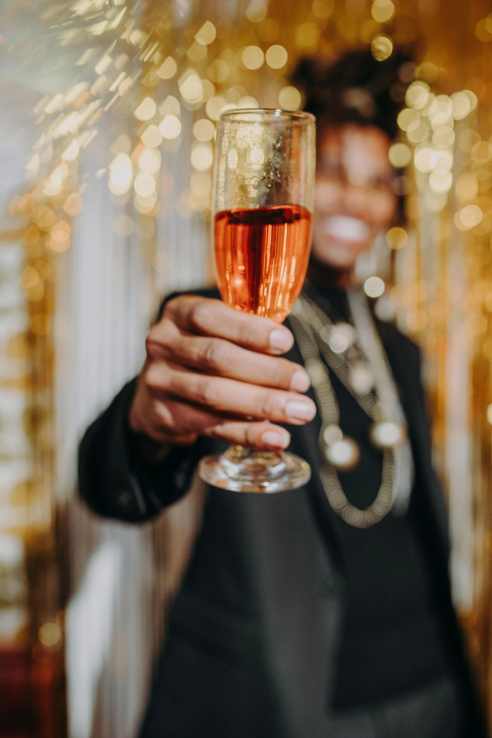 a man in a tuxedo holding a glass of wine, pexels contest winner, renaissance, pink and gold color scheme, new years eve, wearing a gold chain, black man with afro hair