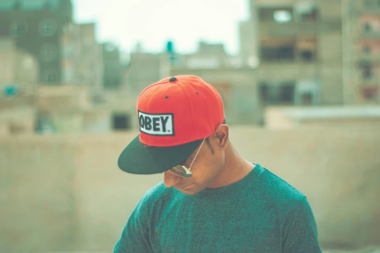 a man wearing a green shirt and a red hat, trending on pexels, \'obey\', grey orange, low profile, rectangle