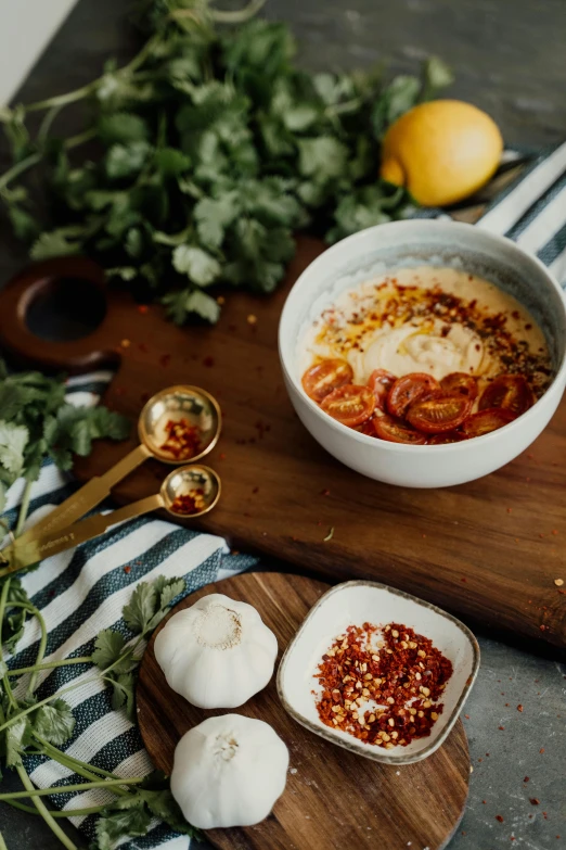 a bowl of soup sitting on top of a wooden cutting board, by Daniel Lieske, hurufiyya, ingredients on the table, gold, humus, high quality product image”