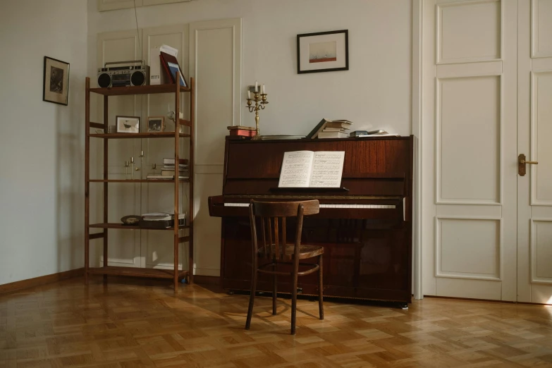 a piano sitting on top of a hard wood floor, inspired by Wilhelm Hammershøi, pexels contest winner, neoclassicism, book shelf small library, in a white room, brown, overview