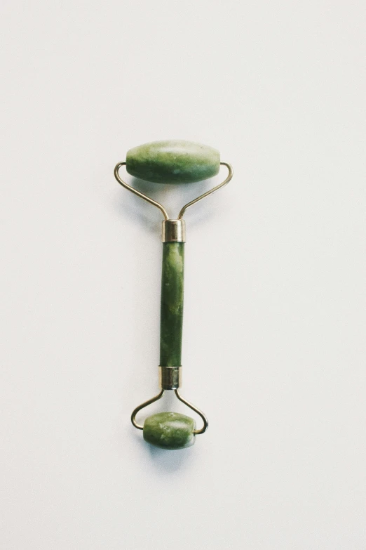 a green jade roller on a white background, unsplash, bauhaus, weathered olive skin, metal handles, late 2000’s, 8