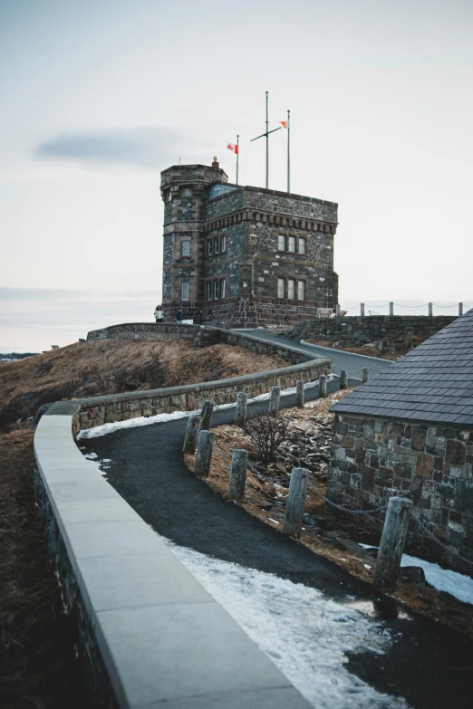 a stone building sitting on top of a hill, nordic crown, overlooking the ocean, with walkways, album