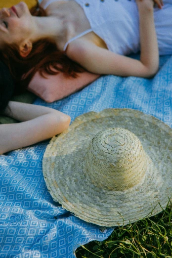 a woman laying on a blanket with a straw hat, by Elsa Bleda, unsplash, two girls, blue, lawn, low detailed