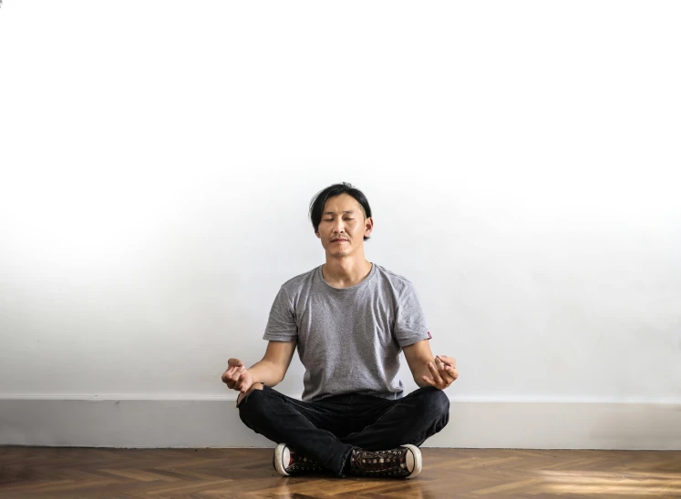 a man sitting in a meditation position on the floor, inspired by Fei Danxu, unsplash, plain background, hammershøi, front facing, asian human