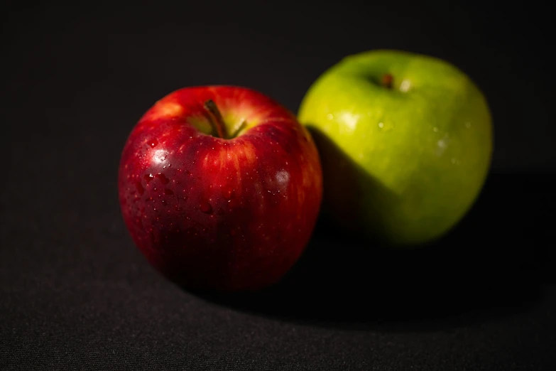 two apples sitting next to each other on a black surface, by Andrew Domachowski, unsplash, shades green and red, mid shot portrait, 15081959 21121991 01012000 4k, close-up product photo