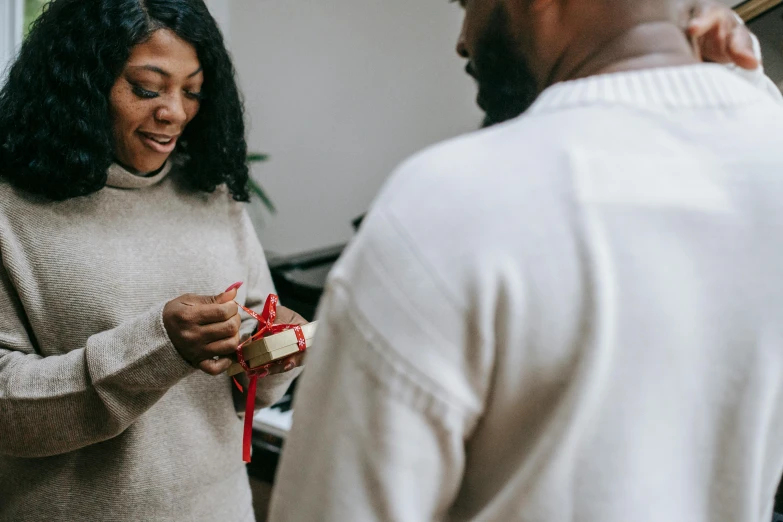 a man standing next to a woman holding a present, by Emma Andijewska, pexels contest winner, happening, photo of a black woman, engagement ring ads, smiling at each other, animated