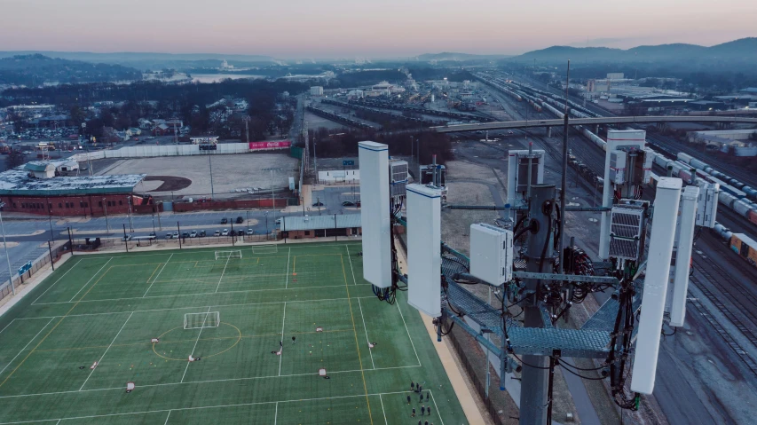 a group of people playing a game of soccer on a field, a matte painting, inspired by Simon Stålenhag, unsplash contest winner, aerial view of a city, antennas, giant speakers, portrait photo