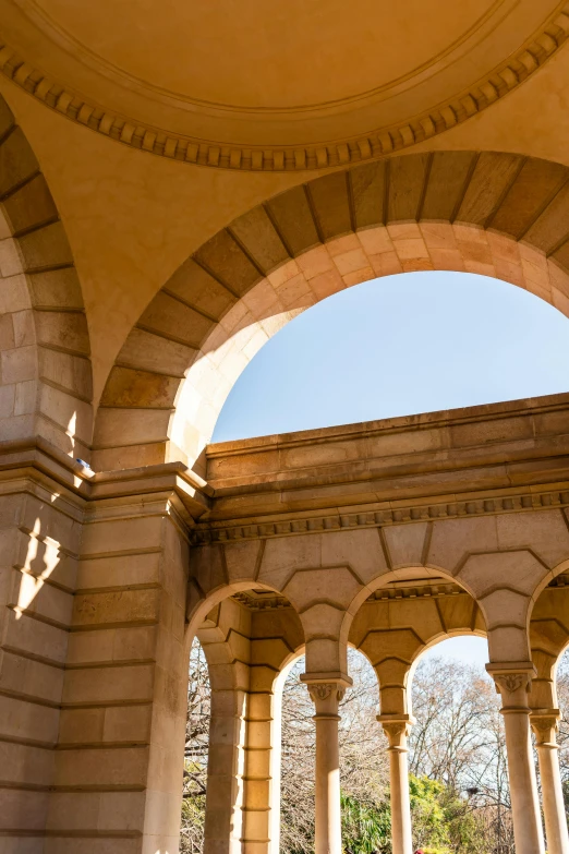 a clock that is on the side of a building, there are archways, full sun, colonnade, inside a crypt