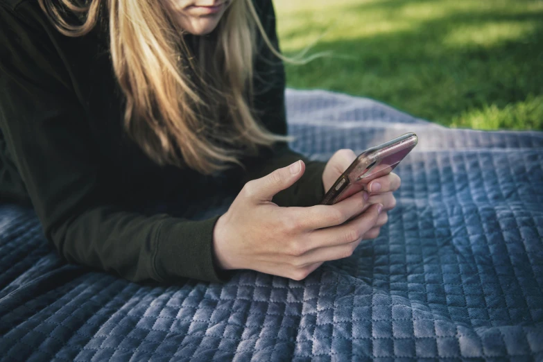 a woman laying on a blanket using a cell phone, trending on pexels, close up of a blonde woman, wearing a dark shirt and jeans, 15081959 21121991 01012000 4k, teenage