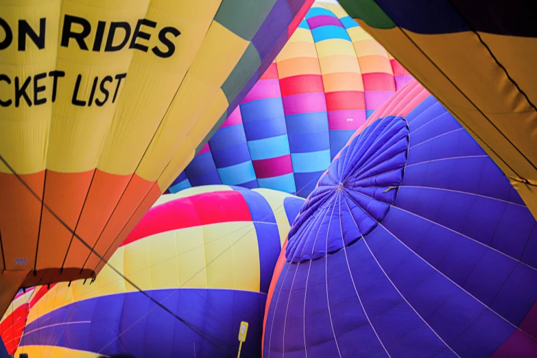 a group of hot air balloons sitting on top of a field, by Raymond Coxon, pexels contest winner, color field, lit from below, banner, purple and yellow, profile shot