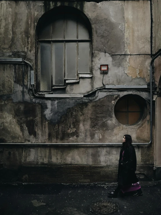 a woman standing in front of an old building, by irakli nadar, pexels contest winner, black overcoat, geometry, street pic, an arab standing watching over