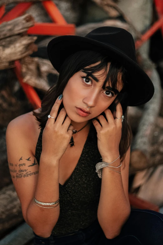 a woman sitting on a bench wearing a hat, by Robbie Trevino, trending on pexels, art nouveau, wearing a bandana and chain, ana de armas portrait, hands on face, square