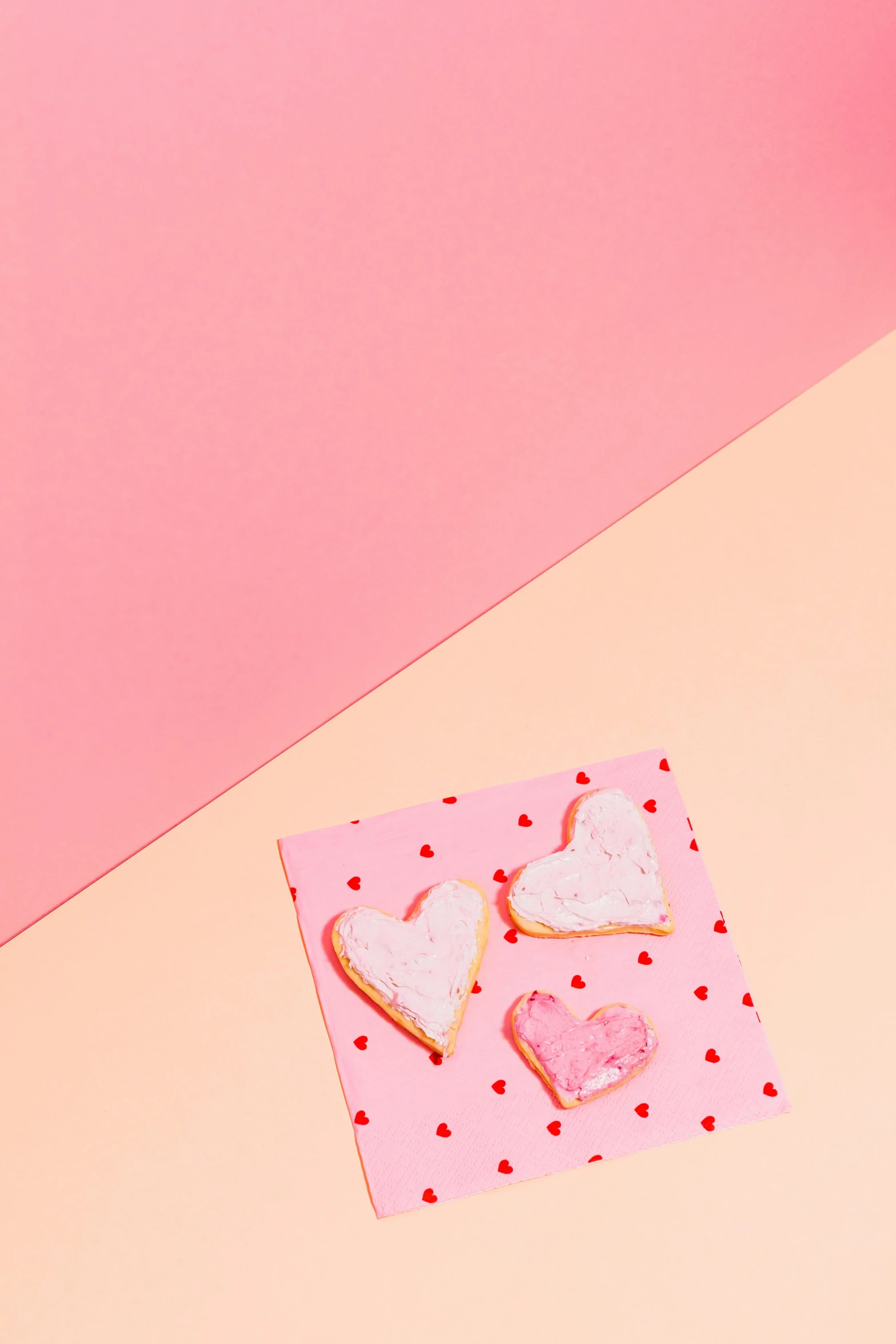 a couple of cookies sitting on top of a pink table, by Julia Pishtar, greeting card, half image, hearts, professional product photo