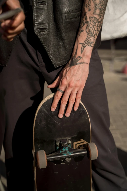a close up of a person holding a skateboard, a tattoo, inspired by L. A. Ring, sitting on man's fingertip, rings, 2 0 5 6, steel skin