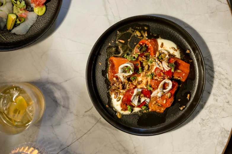 a close up of a plate of food on a table, by Lee Loughridge, black and terracotta, in chippendale sydney, cheesy, sparkling