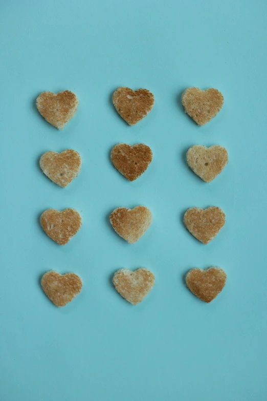 a number of heart shaped cookies on a blue surface, by Sylvia Wishart, minimalism, grain”, 1857, toast, chicken