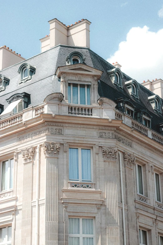 a tall building with a clock on top of it, inspired by Alexandre Falguière, neoclassicism, gambrel roof, awnings, in paris, bay window